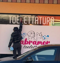 Diletta Scarpellini mentre controlla l'adesivo Labramor sulla vetrina del negozio di toelettatura